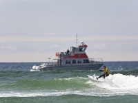A surf competitor rides waves in Cox Bay as a Whale watching boat skirts the inshore waters.