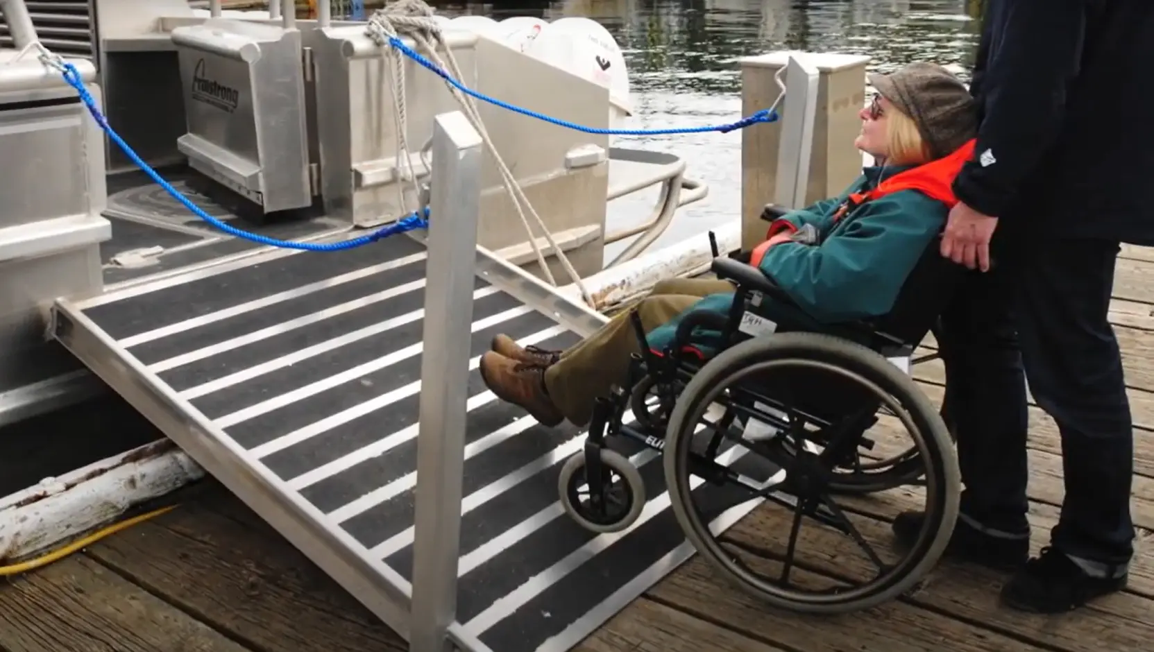 Person in a wheelchair boarding a boat via an accessible ramp.